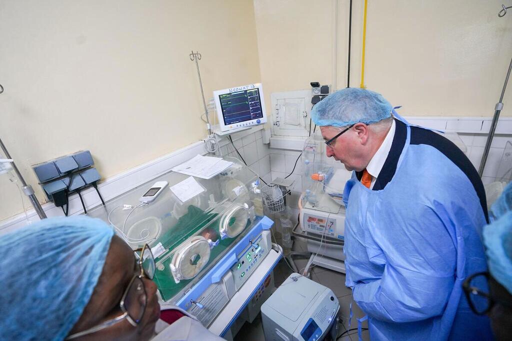 UNFPA Deputy Executive Director Andrew Saberton observes an incubator in a maternity ward at a hospital in Chad, wearing medical attire and a protective cap.