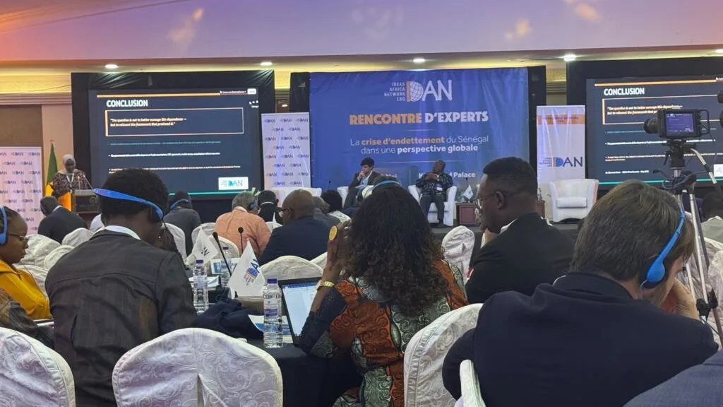Conference on Senegal's debt crisis in progress, featuring panelists and attendees