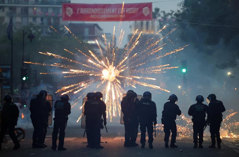 Fireworks explode in front of riot police in Paris on Saturday night.
